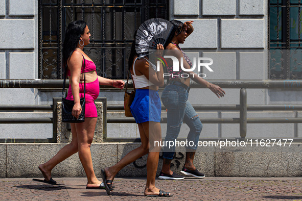 Pedestrians protect themselves from the intense heat in the central region of Sao Paulo, Brazil, on October 1, 2024. 