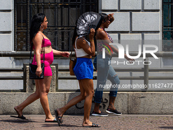 Pedestrians protect themselves from the intense heat in the central region of Sao Paulo, Brazil, on October 1, 2024. (