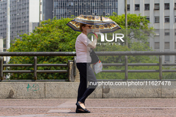 Pedestrians protect themselves from the intense heat in the central region of Sao Paulo, Brazil, on October 1, 2024. 