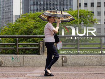 Pedestrians protect themselves from the intense heat in the central region of Sao Paulo, Brazil, on October 1, 2024. (