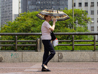 Pedestrians protect themselves from the intense heat in the central region of Sao Paulo, Brazil, on October 1, 2024. (