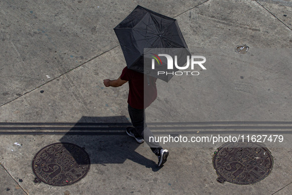 Pedestrians protect themselves from the intense heat in the central region of Sao Paulo, Brazil, on October 1, 2024. 