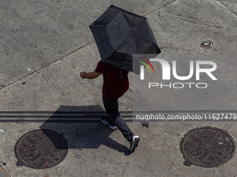 Pedestrians protect themselves from the intense heat in the central region of Sao Paulo, Brazil, on October 1, 2024. (