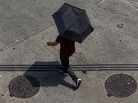 Pedestrians protect themselves from the intense heat in the central region of Sao Paulo, Brazil, on October 1, 2024. (