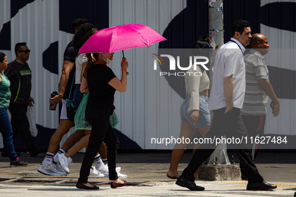 Pedestrians protect themselves from the intense heat in the central region of Sao Paulo, Brazil, on October 1, 2024. 