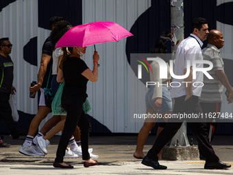 Pedestrians protect themselves from the intense heat in the central region of Sao Paulo, Brazil, on October 1, 2024. (