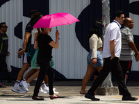 Pedestrians protect themselves from the intense heat in the central region of Sao Paulo, Brazil, on October 1, 2024. (