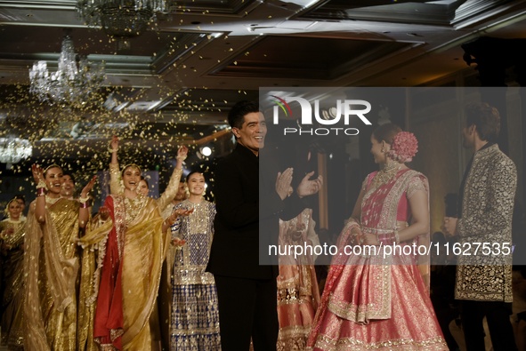 Indian designer Manish Malhotra (L), Bollywood actors Tripti Dimri (C) and Kartik Aryan (R) present a creation by Indian designer Manish Mal...