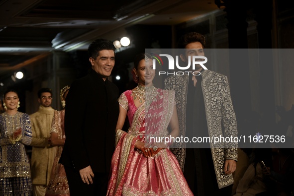 Indian designer Manish Malhotra (L), Bollywood actors Tripti Dimri (C) and Kartik Aryan (R) present a creation by Indian designer Manish Mal...