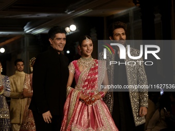 Indian designer Manish Malhotra (L), Bollywood actors Tripti Dimri (C) and Kartik Aryan (R) present a creation by Indian designer Manish Mal...