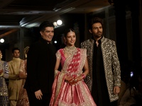 Indian designer Manish Malhotra (L), Bollywood actors Tripti Dimri (C) and Kartik Aryan (R) present a creation by Indian designer Manish Mal...