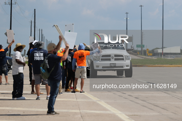 A passing driver holds up his fist in solidarity with a group of striking dockworkers outside the Bayport Container Terminal in Seabrook, Te...