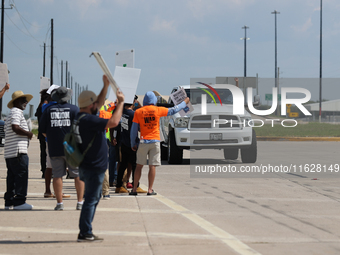 A passing driver holds up his fist in solidarity with a group of striking dockworkers outside the Bayport Container Terminal in Seabrook, Te...