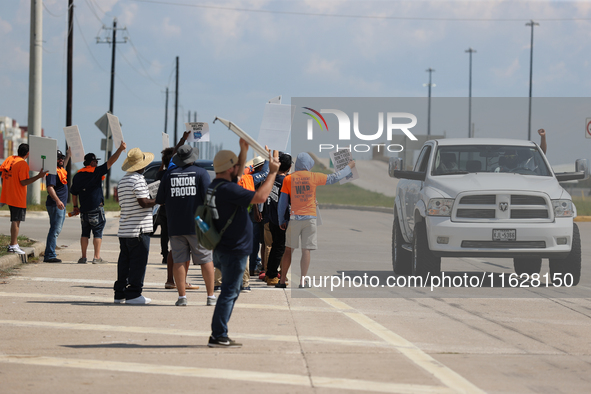 A passing driver holds up his fist in solidarity with a group of striking dockworkers outside the Bayport Container Terminal in Seabrook, Te...