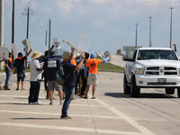 A passing driver holds up his fist in solidarity with a group of striking dockworkers outside the Bayport Container Terminal in Seabrook, Te...