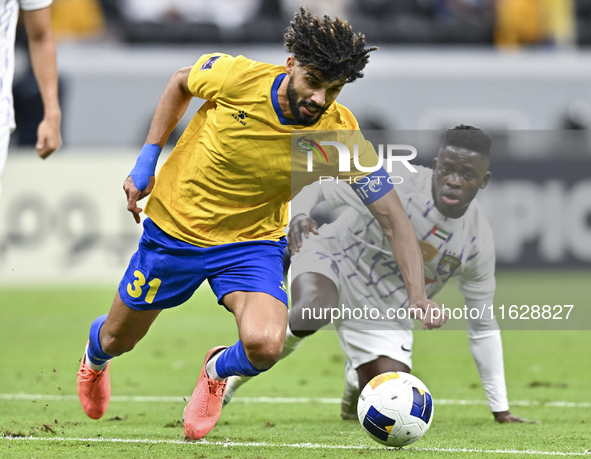 Ferjani Sassi (L) of Al Gharafa SC battles for the ball with Abdoul Karim Traore of Al Ain FC during the AFC Champions League elite west foo...