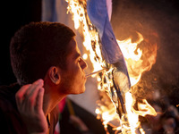 An Iranian man lights a cigarette using a burning Israeli flag while celebrating Iran's missile attack against Israel in Tehran, Iran, on Oc...