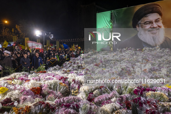 Iranians stand next to a banner featuring a portrait of Lebanon's Hezbollah Secretary General, Hassan Nasrallah, who was killed in an Israel...