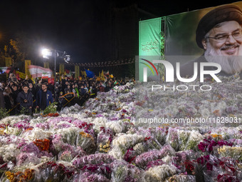 Iranians stand next to a banner featuring a portrait of Lebanon's Hezbollah Secretary General, Hassan Nasrallah, who was killed in an Israel...