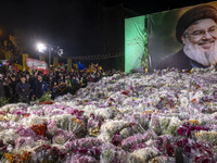 Iranians stand next to a banner featuring a portrait of Lebanon's Hezbollah Secretary General, Hassan Nasrallah, who was killed in an Israel...