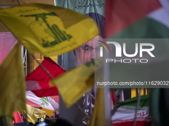 Iranians wave a flag of Lebanon's Hezbollah and a Palestinian flag in front of a portrait of Lebanon's Hezbollah Secretary General, Hassan N...