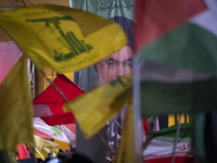 Iranians wave a flag of Lebanon's Hezbollah and a Palestinian flag in front of a portrait of Lebanon's Hezbollah Secretary General, Hassan N...