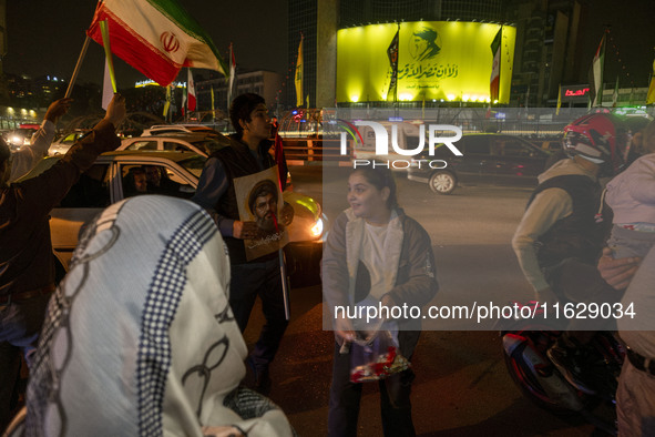 A young Iranian girl who does not wear a mandatory headscarf distributes sweets while celebrating Iran's missile attack against Israel in Te...