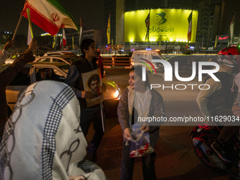 A young Iranian girl who does not wear a mandatory headscarf distributes sweets while celebrating Iran's missile attack against Israel in Te...