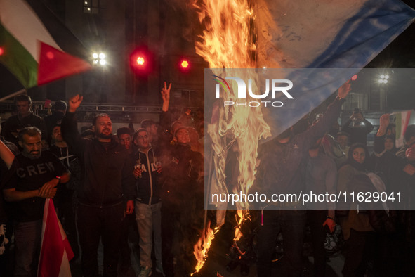 Iranian protesters shout anti-Israeli slogans while burning an Israeli flag in a celebration for Iran's missile attack against Israel, in Te...