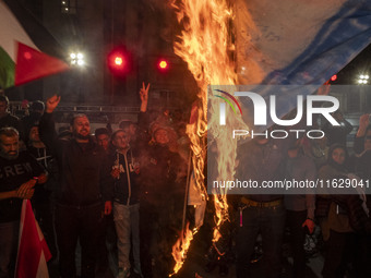 Iranian protesters shout anti-Israeli slogans while burning an Israeli flag in a celebration for Iran's missile attack against Israel, in Te...