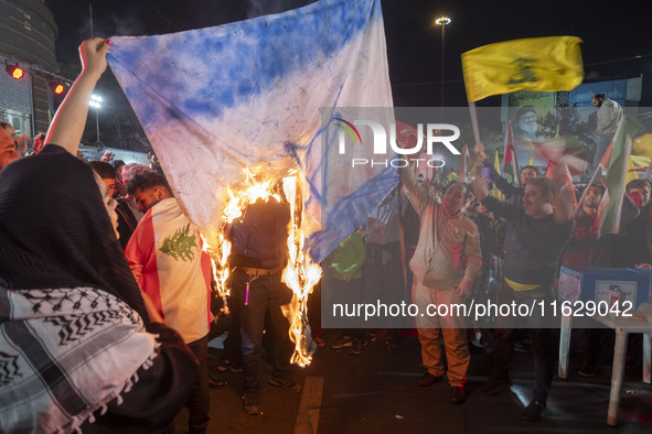 Iranian protesters shout anti-Israeli slogans while burning an Israeli flag in a celebration for Iran's missile attack against Israel, in Te...