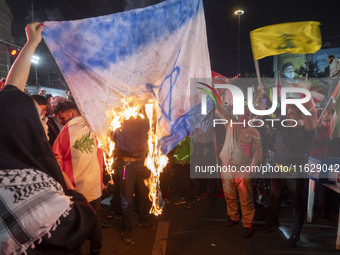 Iranian protesters shout anti-Israeli slogans while burning an Israeli flag in a celebration for Iran's missile attack against Israel, in Te...