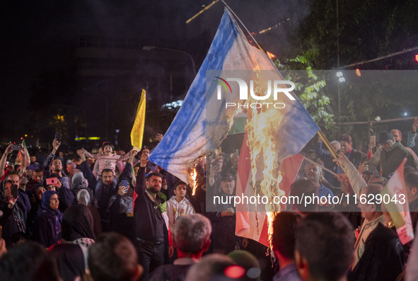 Iranian protesters shout anti-Israeli slogans while burning an Israeli flag in a celebration for Iran's missile attack against Israel, in Te...