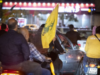 A veiled Iranian woman sits on a motorcycle, carrying a flag of Lebanon's Hezbollah, while celebrating Iran's missile attack against Israel,...