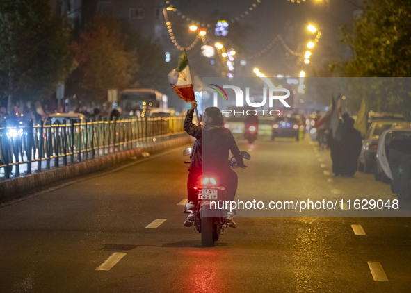 A motorcyclist carries an Iranian flag while celebrating Iran's missile attack against Israel in Tehran, Iran, on October 1, 2024. Iran laun...