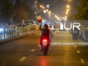 A motorcyclist carries an Iranian flag while celebrating Iran's missile attack against Israel in Tehran, Iran, on October 1, 2024. Iran laun...