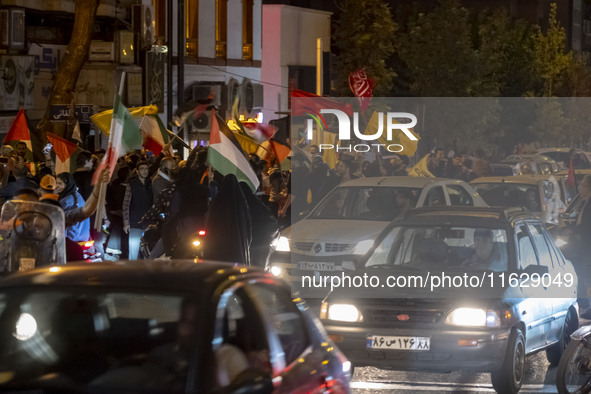 Iranians wave Lebanon's Hezbollah flags and a Palestinian flag while celebrating Iran's missile attack against Israel in Tehran, Iran, on Oc...