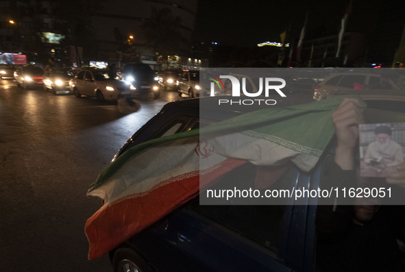 An Iranian man waves an Iranian flag while celebrating Iran's missile attack against Israel in Tehran, Iran, on October 1, 2024. Iran launch...