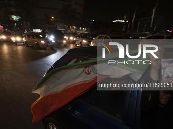 An Iranian man waves an Iranian flag while celebrating Iran's missile attack against Israel in Tehran, Iran, on October 1, 2024. Iran launch...