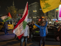 Iranian men wave Lebanon's Hezbollah flag, a Lebanese flag, and a Palestinian flag while celebrating Iran's missile attack against Israel in...