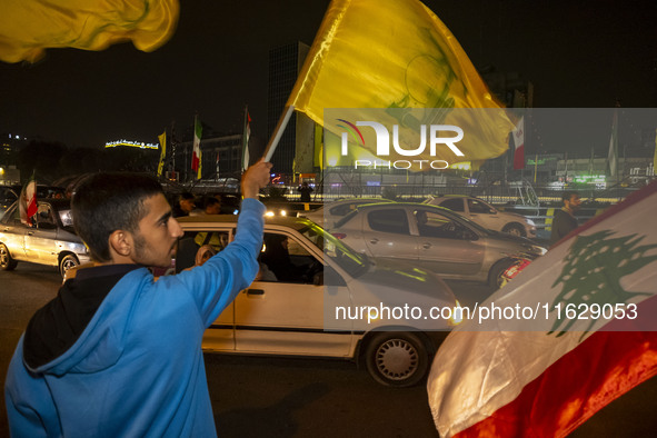 Iranian men wave a Hezbollah flag and a Palestinian flag while celebrating Iran's missile attack against Israel in Tehran, Iran, on October...