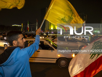 Iranian men wave a Hezbollah flag and a Palestinian flag while celebrating Iran's missile attack against Israel in Tehran, Iran, on October...