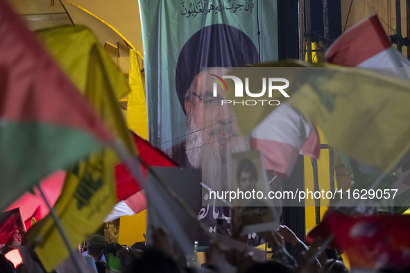 Iranians wave flags of Lebanon's Hezbollah and Palestine in front of a portrait of Lebanon's Hezbollah Secretary General, Hassan Nasrallah,...