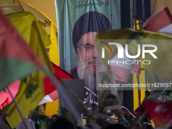 Iranians wave flags of Lebanon's Hezbollah and Palestine in front of a portrait of Lebanon's Hezbollah Secretary General, Hassan Nasrallah,...