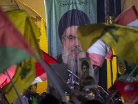 Iranians wave flags of Lebanon's Hezbollah and Palestine in front of a portrait of Lebanon's Hezbollah Secretary General, Hassan Nasrallah,...