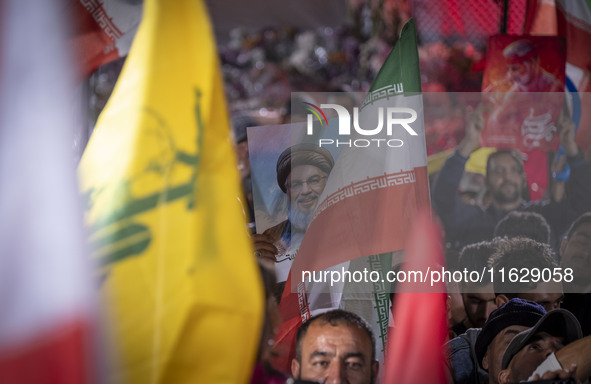 An Iranian man holds a portrait of Lebanon's Hezbollah Secretary General, Hassan Nasrallah, who was killed in an Israeli air strike in the s...