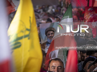 An Iranian man holds a portrait of Lebanon's Hezbollah Secretary General, Hassan Nasrallah, who was killed in an Israeli air strike in the s...