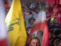 An Iranian man holds a portrait of Lebanon's Hezbollah Secretary General, Hassan Nasrallah, who was killed in an Israeli air strike in the s...