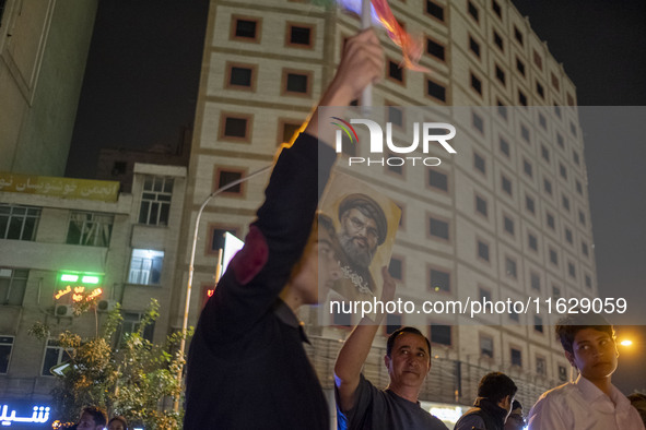 An Iranian man holds a portrait of Lebanon's Hezbollah Secretary General, Hassan Nasrallah, who was killed in an Israeli air strike in the s...