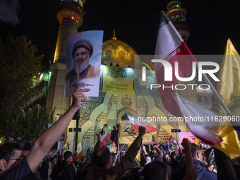 An Iranian man holds a portrait of Lebanon's Hezbollah Secretary General, Hassan Nasrallah, who was killed in an Israeli air strike in the s...